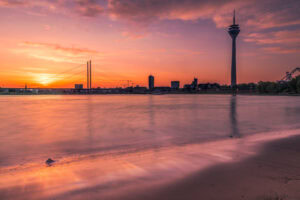 Fine-Art-Print Düsseldorf Skyline mit Rheinturm und Sonnenaufgang über dem Rhein, aufgenommen in sanfter Langzeitbelichtung, erhältlich als hochwertiger Kunstdruck.