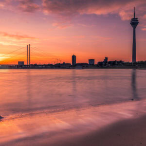 Fine-Art-Print Düsseldorf Skyline mit Rheinturm und Sonnenaufgang über dem Rhein, aufgenommen in sanfter Langzeitbelichtung, erhältlich als hochwertiger Kunstdruck.