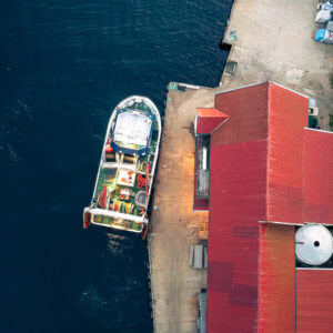Fine-Art-Print Luftaufnahme Bootsanleger mit rotem Dach auf der Insel Hidra in Norwegen, erhältlich als hochwertiger Kunstdruck