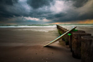 Fine-Art-Print Surfbrett am Weststrand der Ostsee während einer Gewitterstimmung, erhältlich als hochwertiger Kunstdruck.
