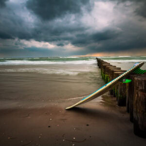 Fine-Art-Print Surfbrett am Weststrand der Ostsee während einer Gewitterstimmung, erhältlich als hochwertiger Kunstdruck.