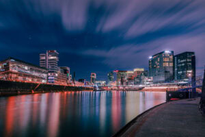 Fine Art Print der Düsseldorfer Medienhafen Skyline bei Nacht mit leuchtender Langzeitbelichtung und spiegelglattem Wasser.