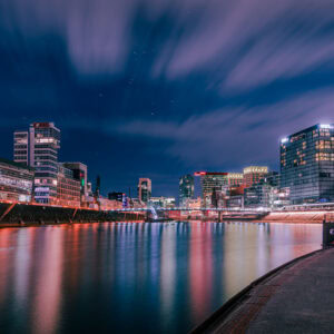 Fine Art Print der Düsseldorfer Medienhafen Skyline bei Nacht mit leuchtender Langzeitbelichtung und spiegelglattem Wasser.