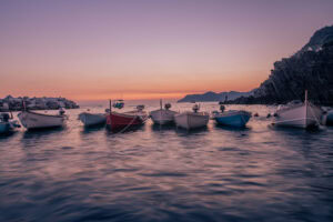 Riomaggiore, Cinque Terre – Fischerboote im Hafen bei Sonnenuntergang, sanfte Wasserbewegung.