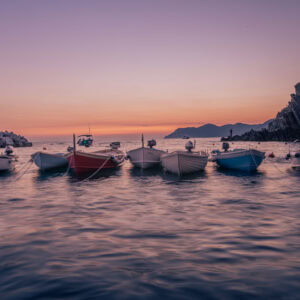 Riomaggiore, Cinque Terre – Fischerboote im Hafen bei Sonnenuntergang, sanfte Wasserbewegung.