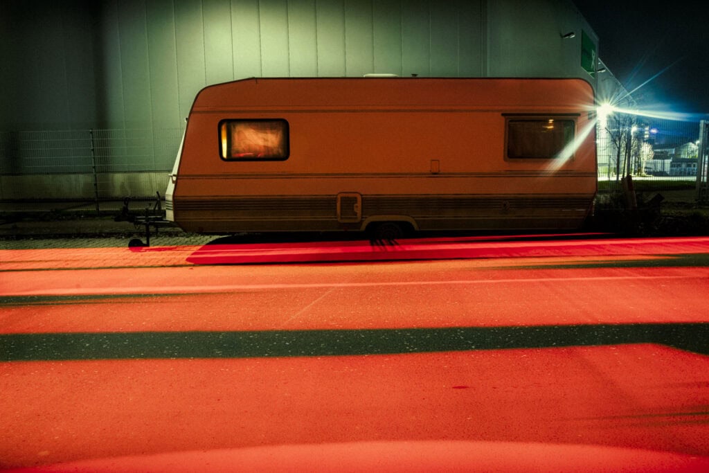 Düsseldorf Industriehafen – Wohnwagen vor Halle, rotes Lichtband, Nacht, Langzeitbelichtung.