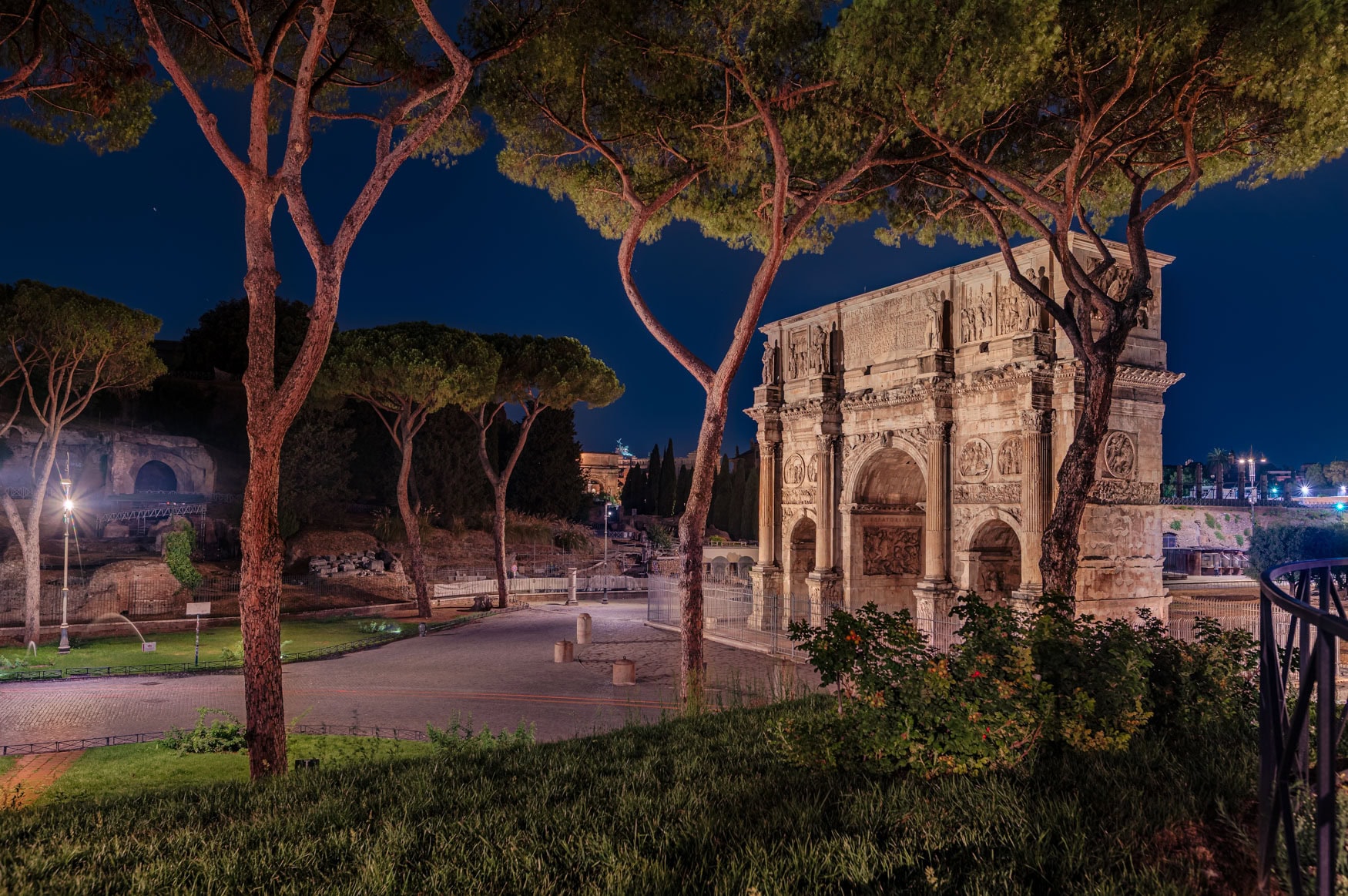 Rom – Konstantinsbogen bei Nacht, von Schirmpinien gerahmt, klare Beleuchtung, ruhige Stimmung.