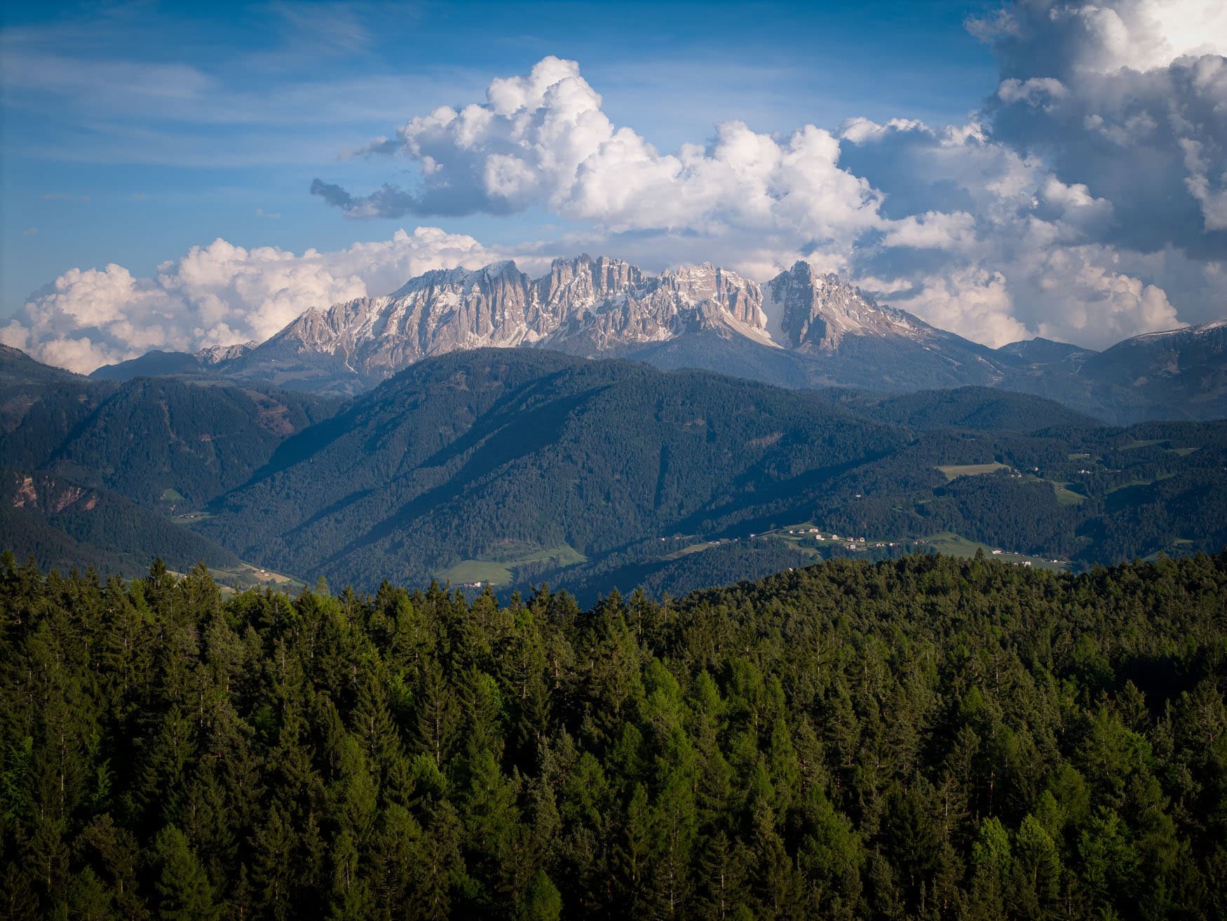 Oberbozen, Südtirol – Luftaufnahme mit Blick auf Dolomiten, Waldsaum und Wolkentürme, klare Staffeln.