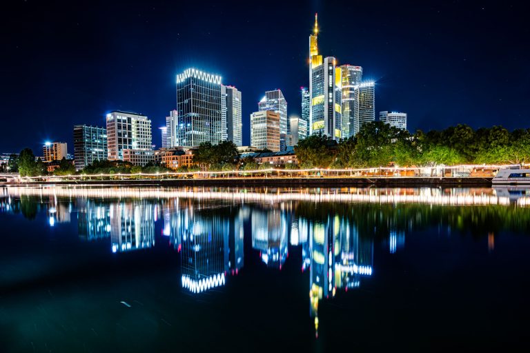 Nachts beleuchtete Skyline von Frankfurt mit Reflexion im ruhigen Mainufer