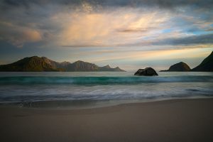 Sanfte Wellen am Hauklandstrand auf den Lofoten vor Bergen bei Abendlicht
