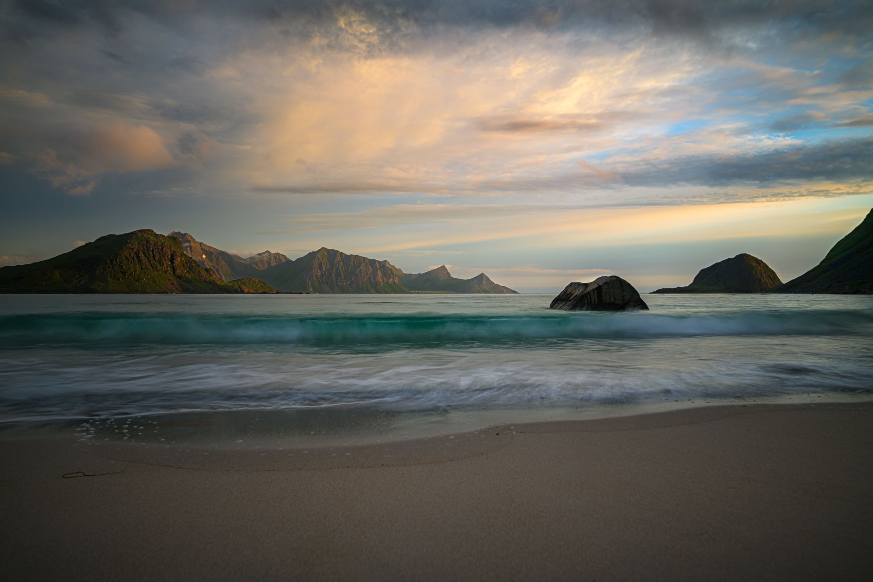 Sanfte Wellen am Hauklandstrand auf den Lofoten vor Bergen bei Abendlicht
