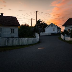 Ruhige Dorfstraße mit weißen Holzhäusern bei Sonnenuntergang