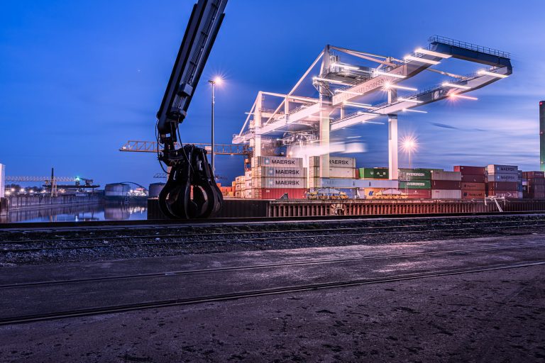 Beleuchteter Containerhafen mit Kran im Düsseldorfer Industriehafen zur Blauen Stunde