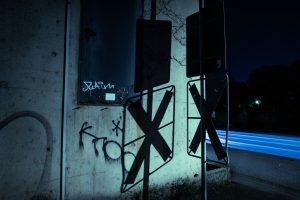 Straßenschilder, Graffiti und blaue Lichtspuren im nächtlichen Düsseldorfer Industriehafen