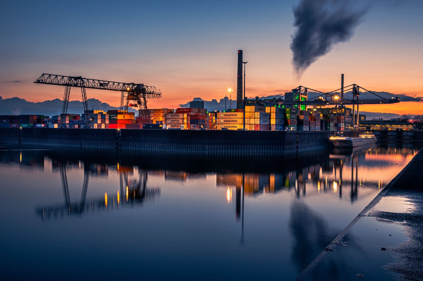 Industriehafen in Düsseldorf mit Containern und Kränen im Sonnenuntergang, Spiegelung im Hafenbecken