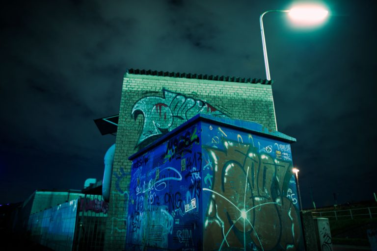 Graffiti-besprühter Bau im Düsseldorfer Industriehafen bei Nacht unter Straßenlaterne