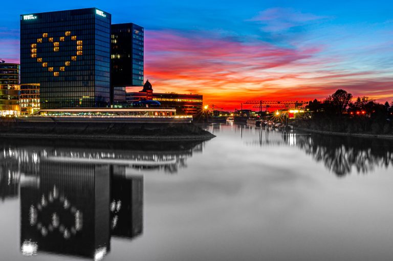 Düsseldorf Medienhafen bei Sonnenuntergang mit beleuchtetem Hochhaus und Herzmotiv am Wasser