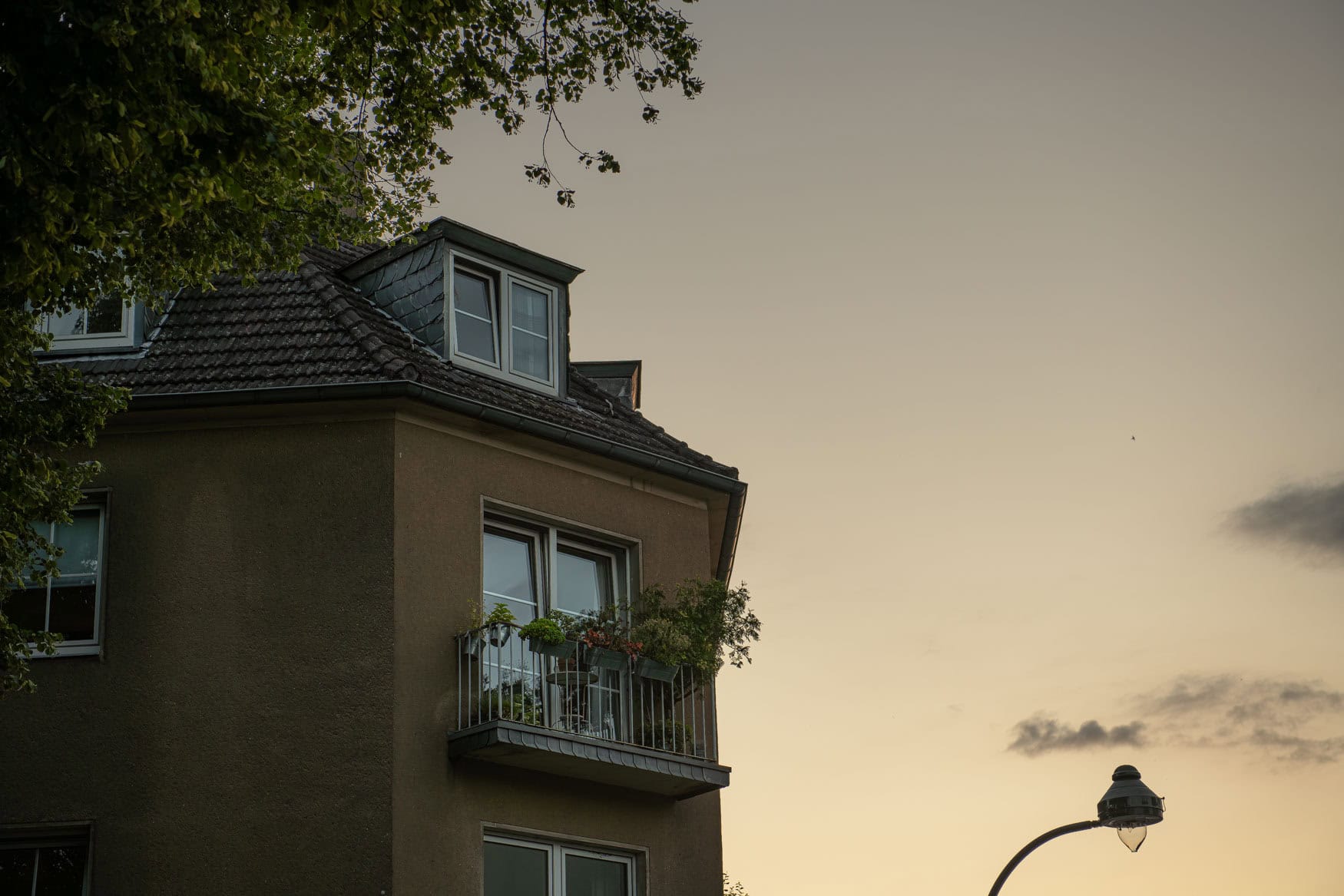 Altbau-Balkon mit Pflanzen in Düsseldorf Oberkassel vor stillem Abendhimmel