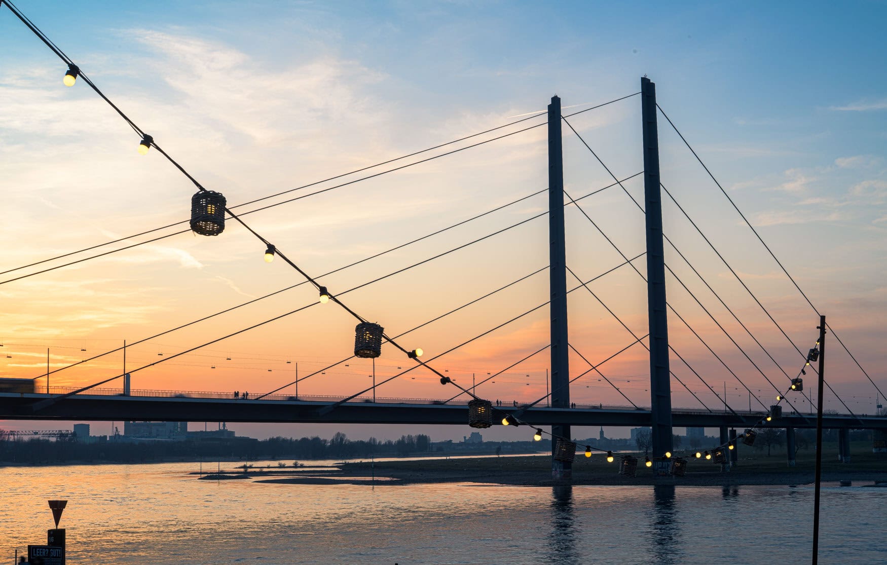 Rheinkniebrücke in Düsseldorf bei Sonnenuntergang mit Lichterkette am Rheinufer