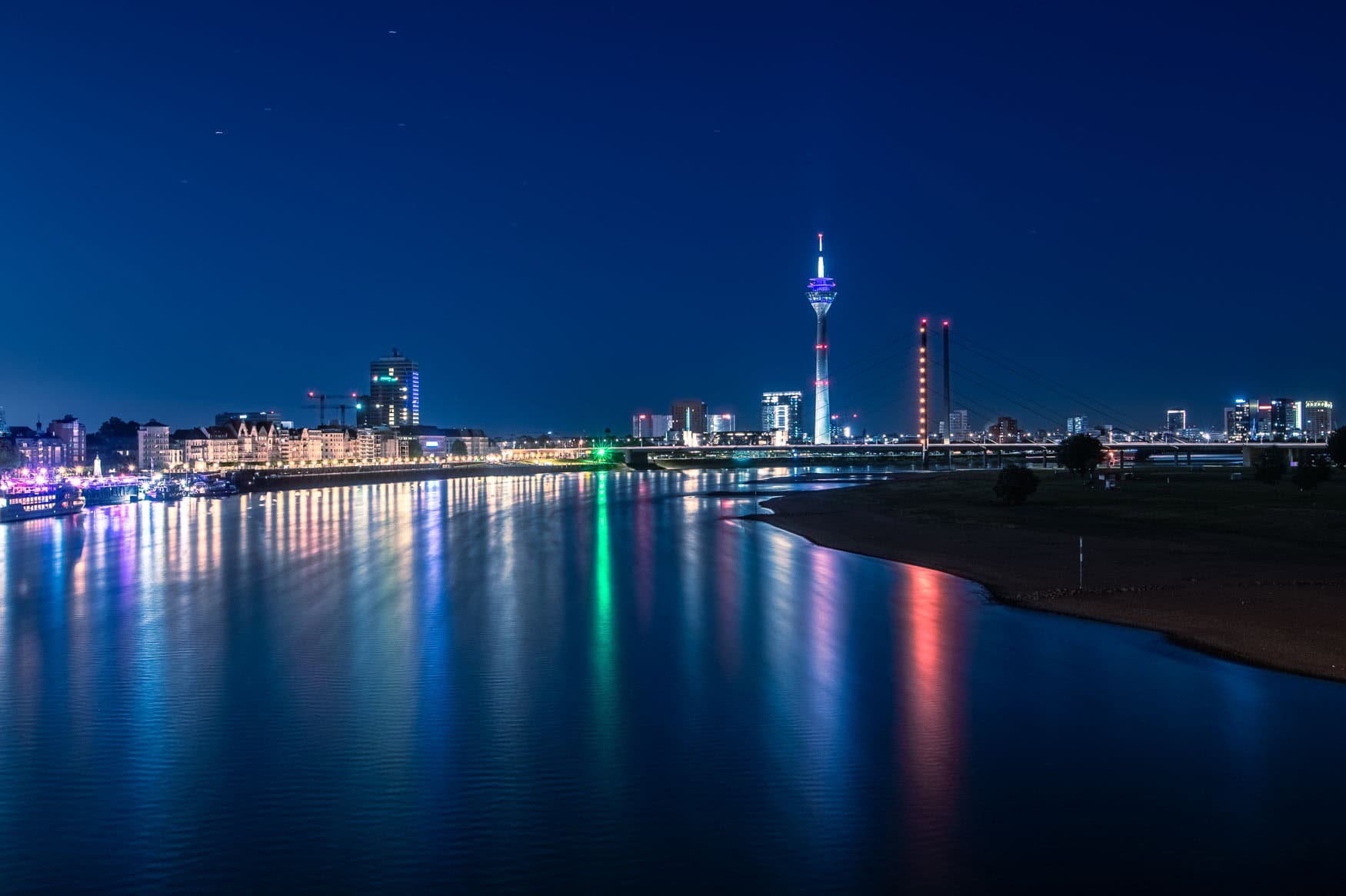 Nachtaufnahme der Düsseldorfer Skyline mit Rhein, Rheinturm und Brücke