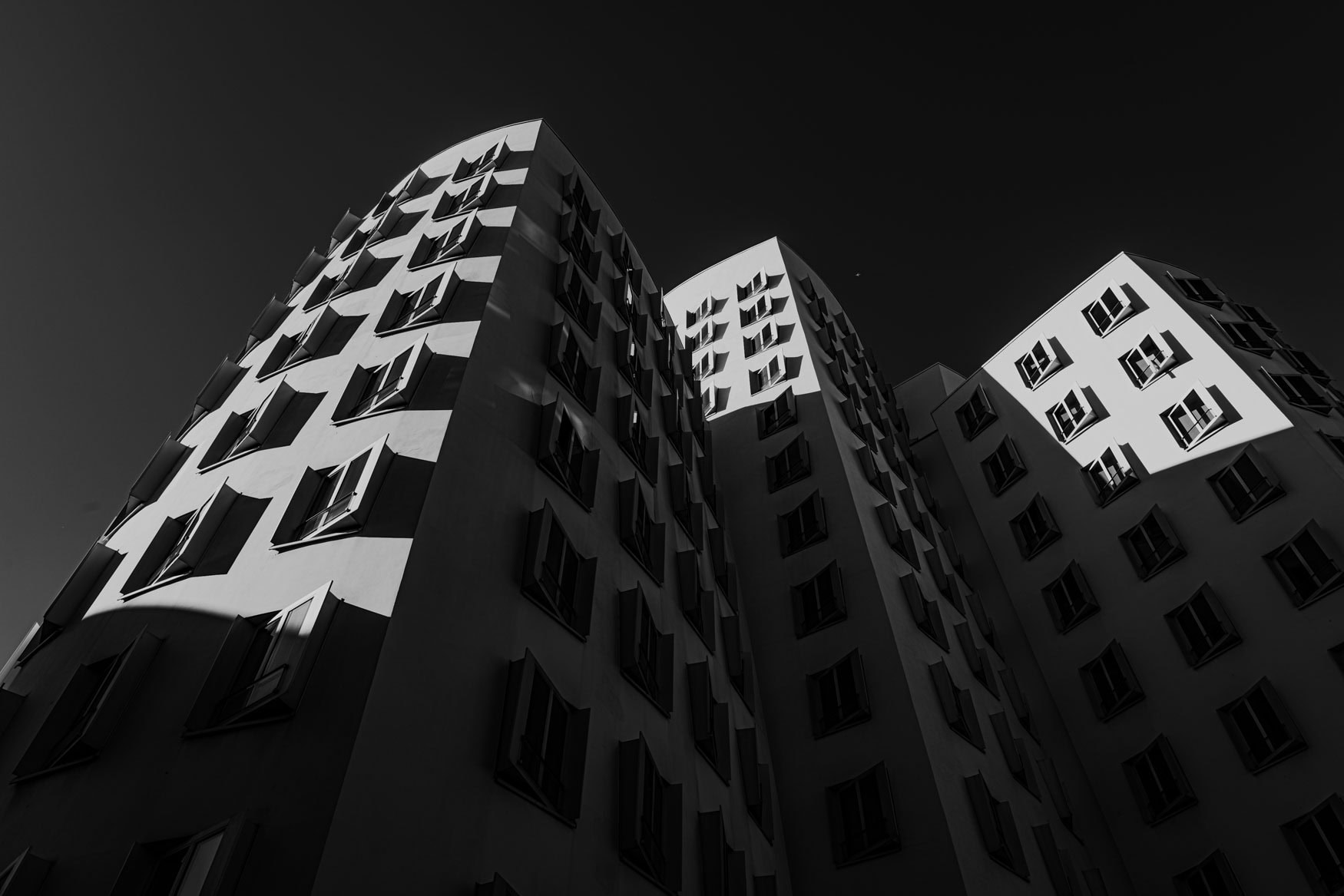 Schwarzweißfotografie der geschwungenen Gehry Bauten in Düsseldorf mit starkem Licht-Schatten-Kontrast