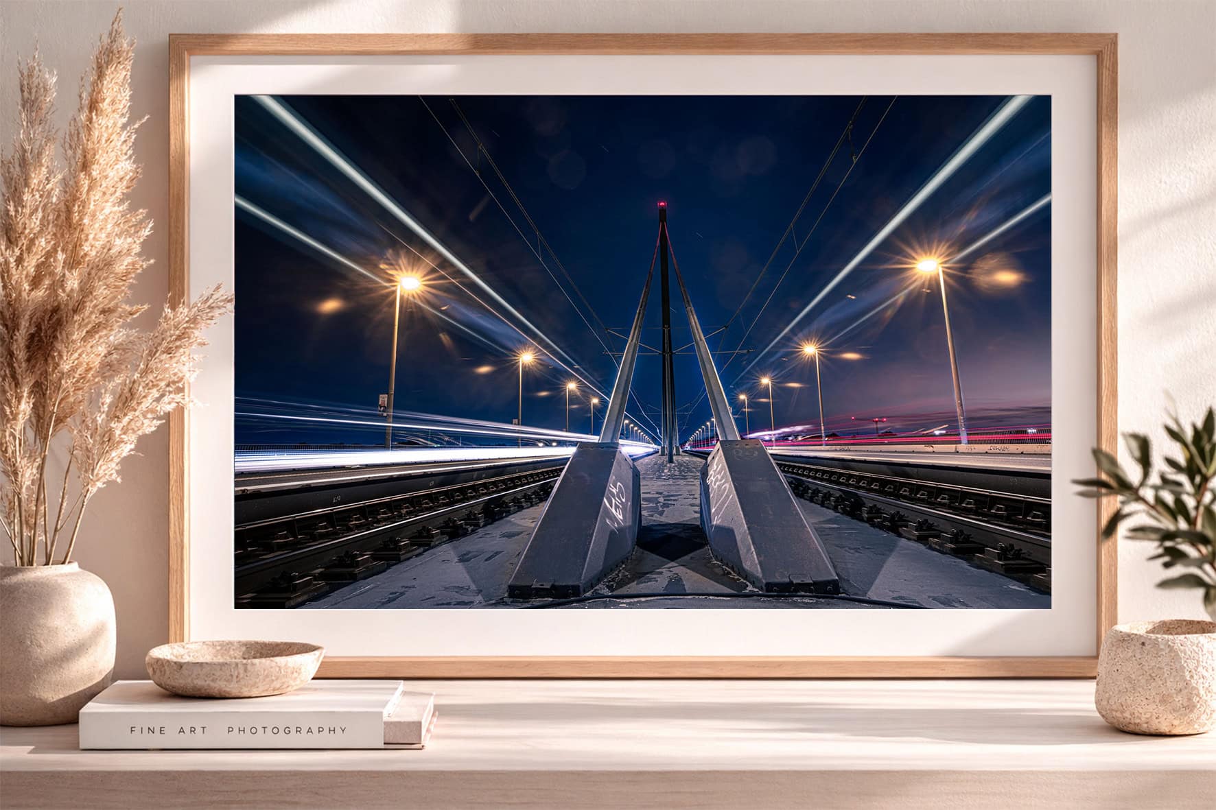 Fotografie einer modernen Brücke mit Bahntrassen bei Nacht, symmetrische Perspektive, Lichtspuren und Straßenlaternen im Holzrahmen
