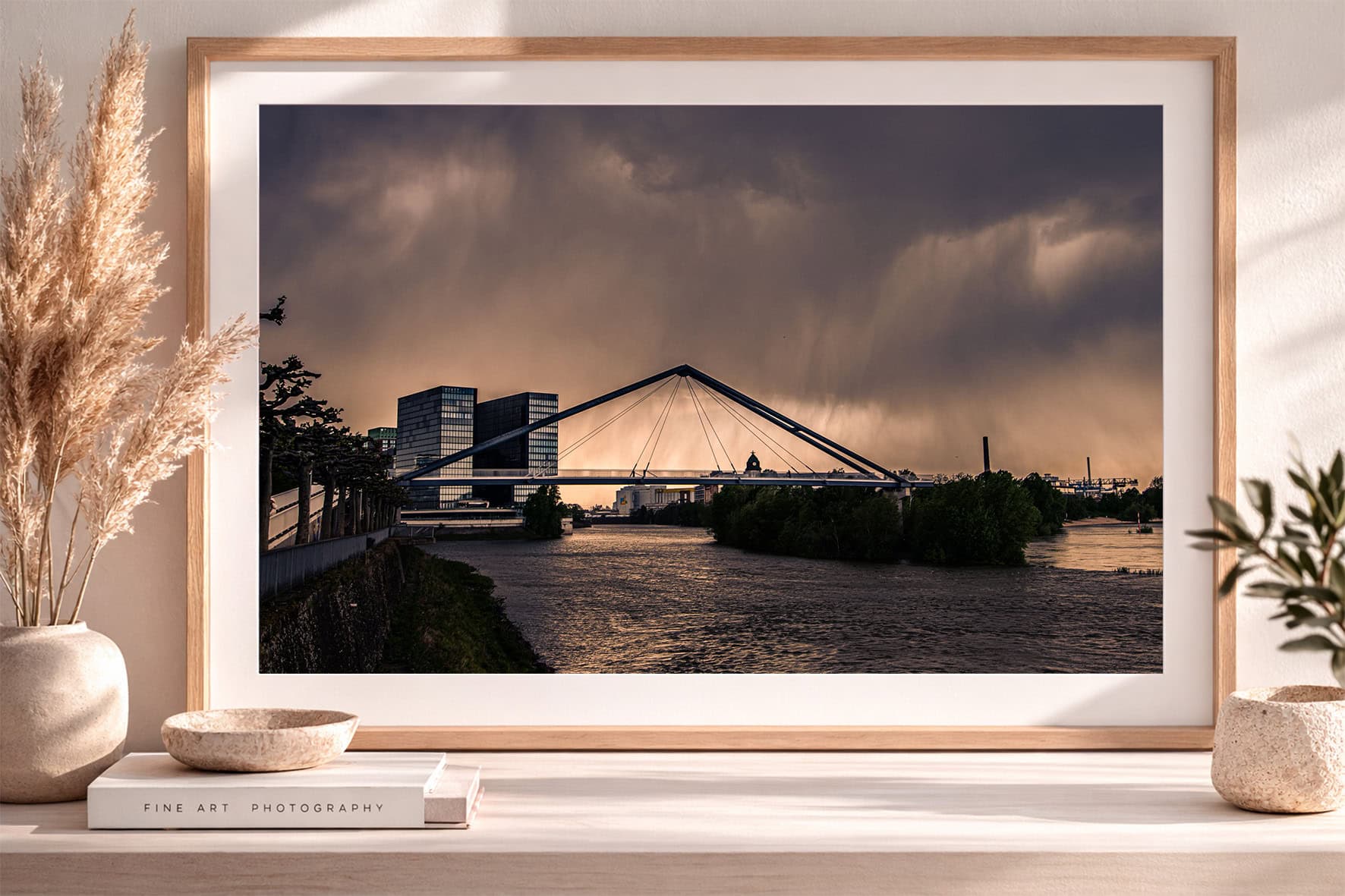 Fotografie einer modernen Brücke über einem Fluss vor Glasgebäuden bei dramatischem Abendhimmel in hellem, skandinavischem Interior