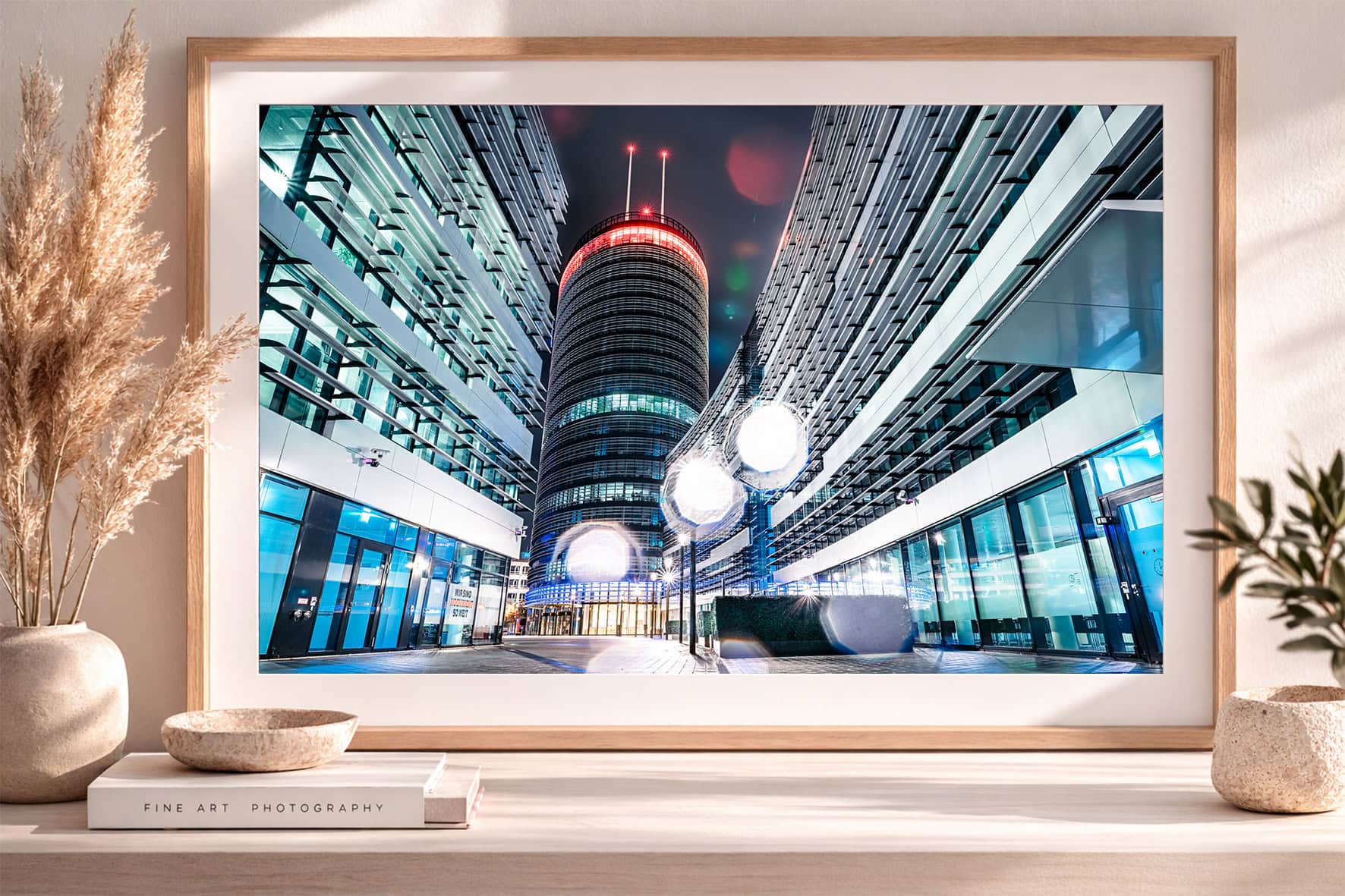 Fine-Art-Fotografie eines beleuchteten Rundturms zwischen zwei modernen Bürogebäuden bei Nacht im Rahmen auf Sideboard