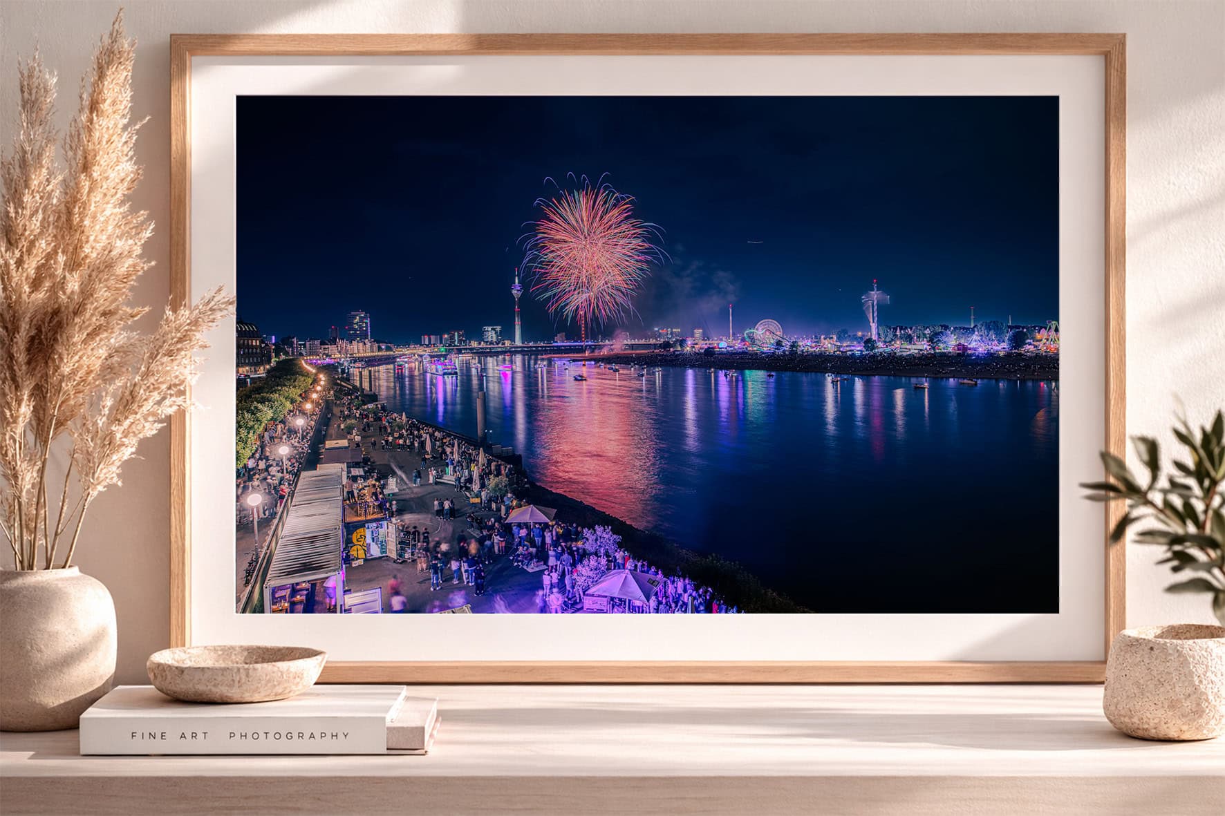Fotografie mit Feuerwerk über einer hell erleuchteten Fluss-Promenade bei Nacht, im Holzrahmen auf einem Sideboard dekoriert.