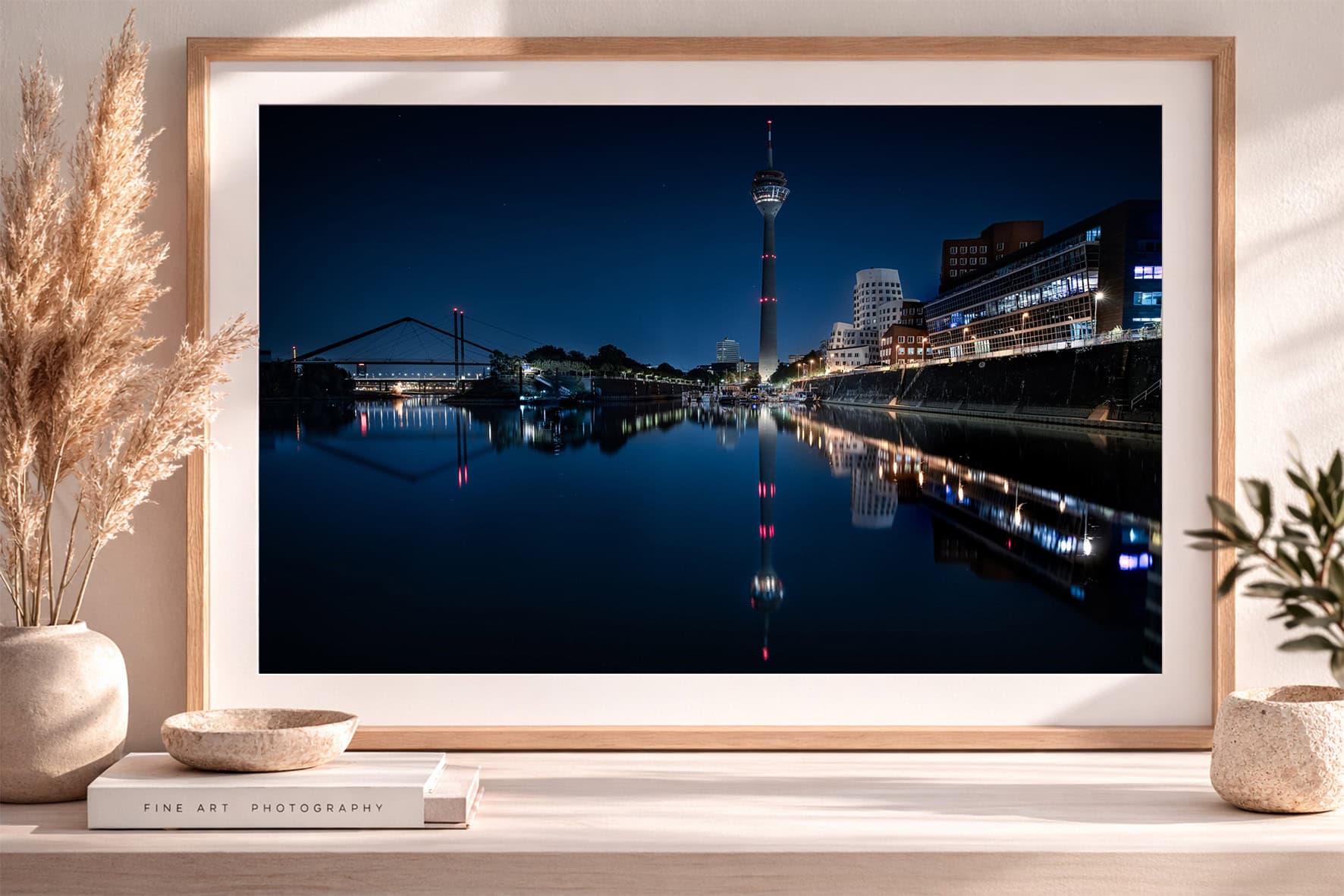 Großformatiger Stadtansicht-Kunstdruck bei Nacht mit beleuchteter Skyline und klaren Spiegelungen im ruhigen Fluss in hellem Interior