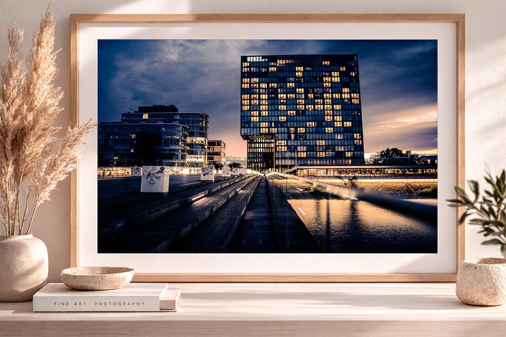Großformatiges Stadtfotografie-Wandbild mit moderner Architektur am Wasser, beleuchteten Fenstern und Abendhimmel in hellem Interior