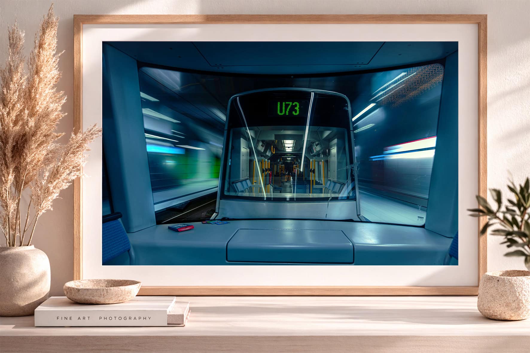 Großformatiges Foto einer U-Bahnfront mit Anzeige U73 im beleuchteten Tunnel, gerahmt in hellem Holzrahmen auf Sideboard