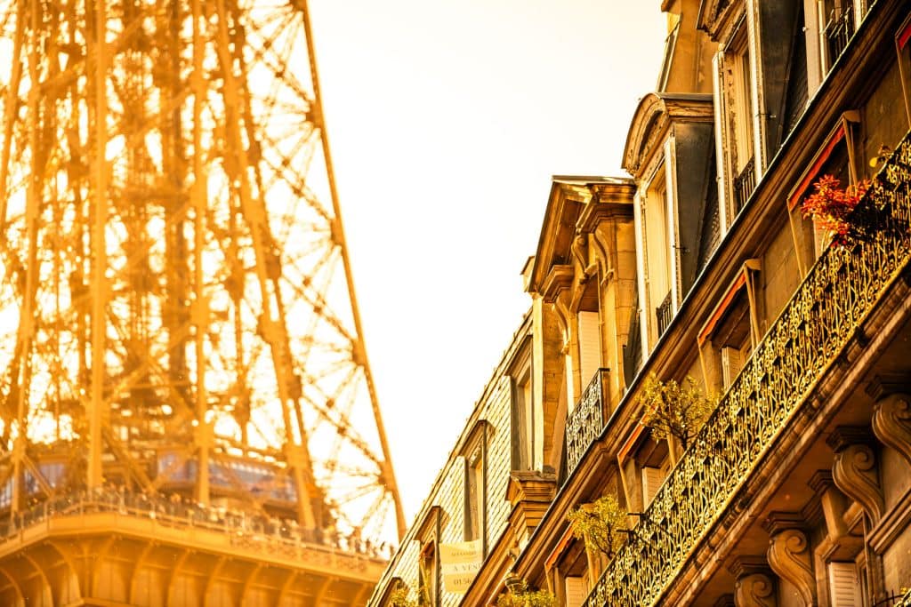 Eiffelturm in Paris neben Hausfassaden und Balkonen im warmen goldenen Sonnenuntergang