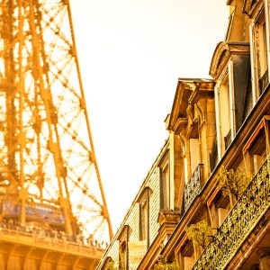 Eiffelturm in Paris neben Hausfassaden und Balkonen im warmen goldenen Sonnenuntergang