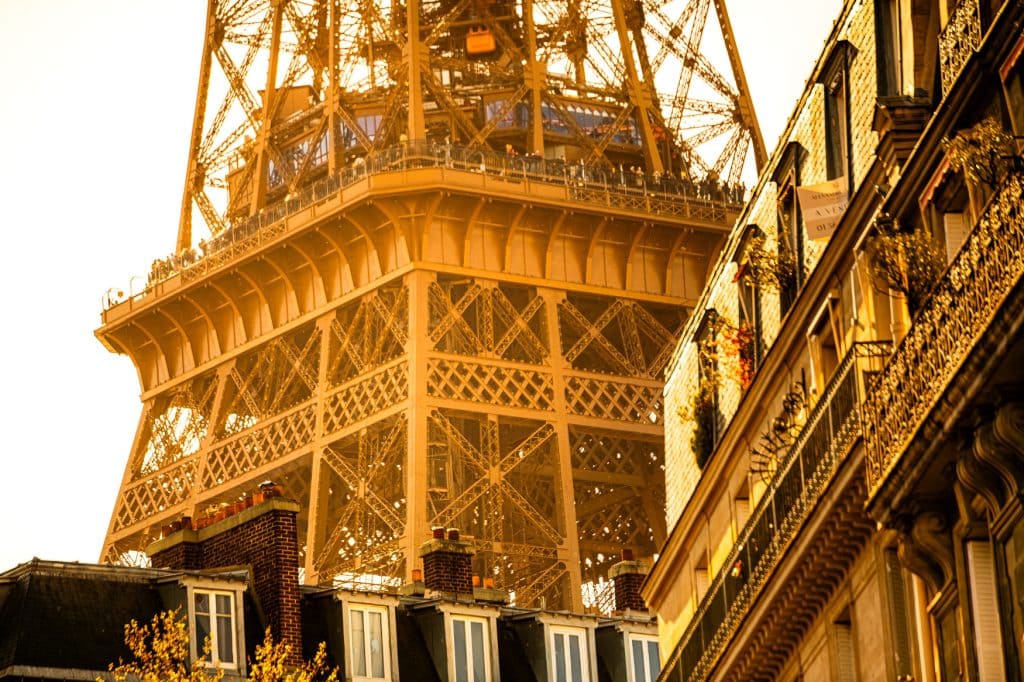 Eiffelturm in Paris als Architekturdetail zwischen Hausfassaden im warmen goldenen Licht