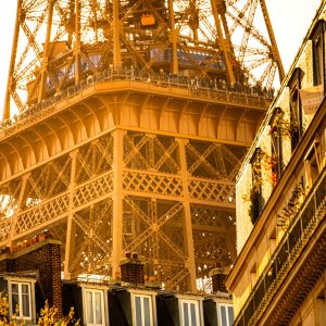 Eiffelturm in Paris als Architekturdetail zwischen Hausfassaden im warmen goldenen Licht