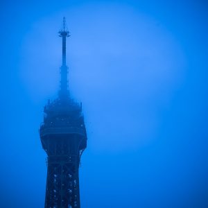 Spitze des Eiffelturms in Paris, von blauem Nebel umhüllt zur Blauen Stunde