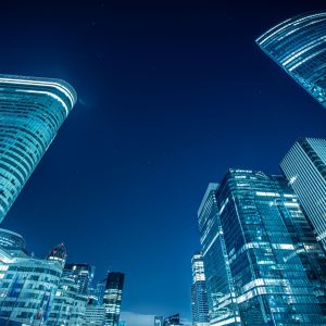 Blick nach oben auf beleuchtete Hochhäuser in Paris La Défense bei Nacht mit abstrakter Perspektive