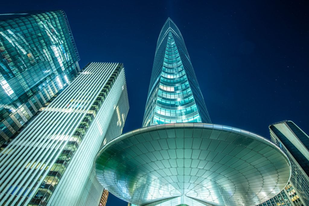 Wolkenkratzer in Paris La Défense bei Nacht aus der Froschperspektive mit beleuchteten Glasfassaden