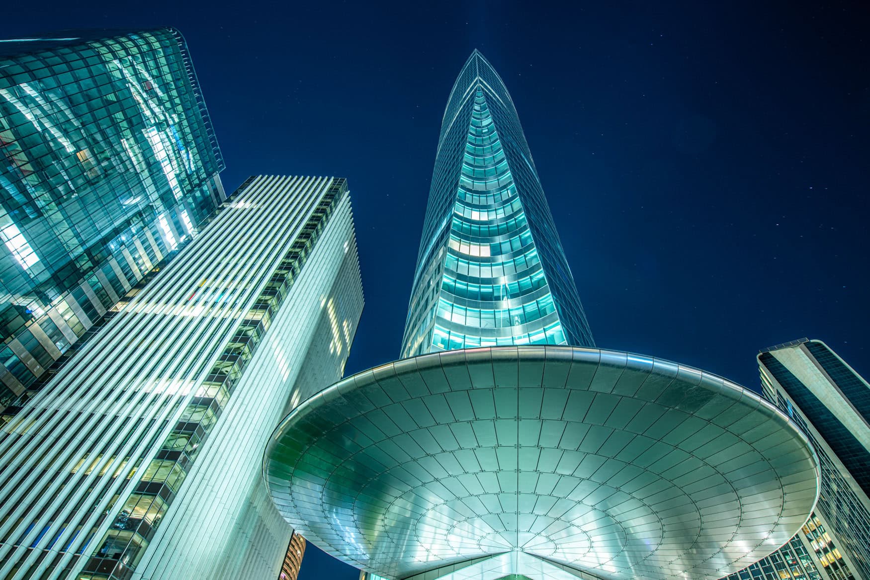 Wolkenkratzer in Paris La Défense bei Nacht aus der Froschperspektive mit beleuchteten Glasfassaden