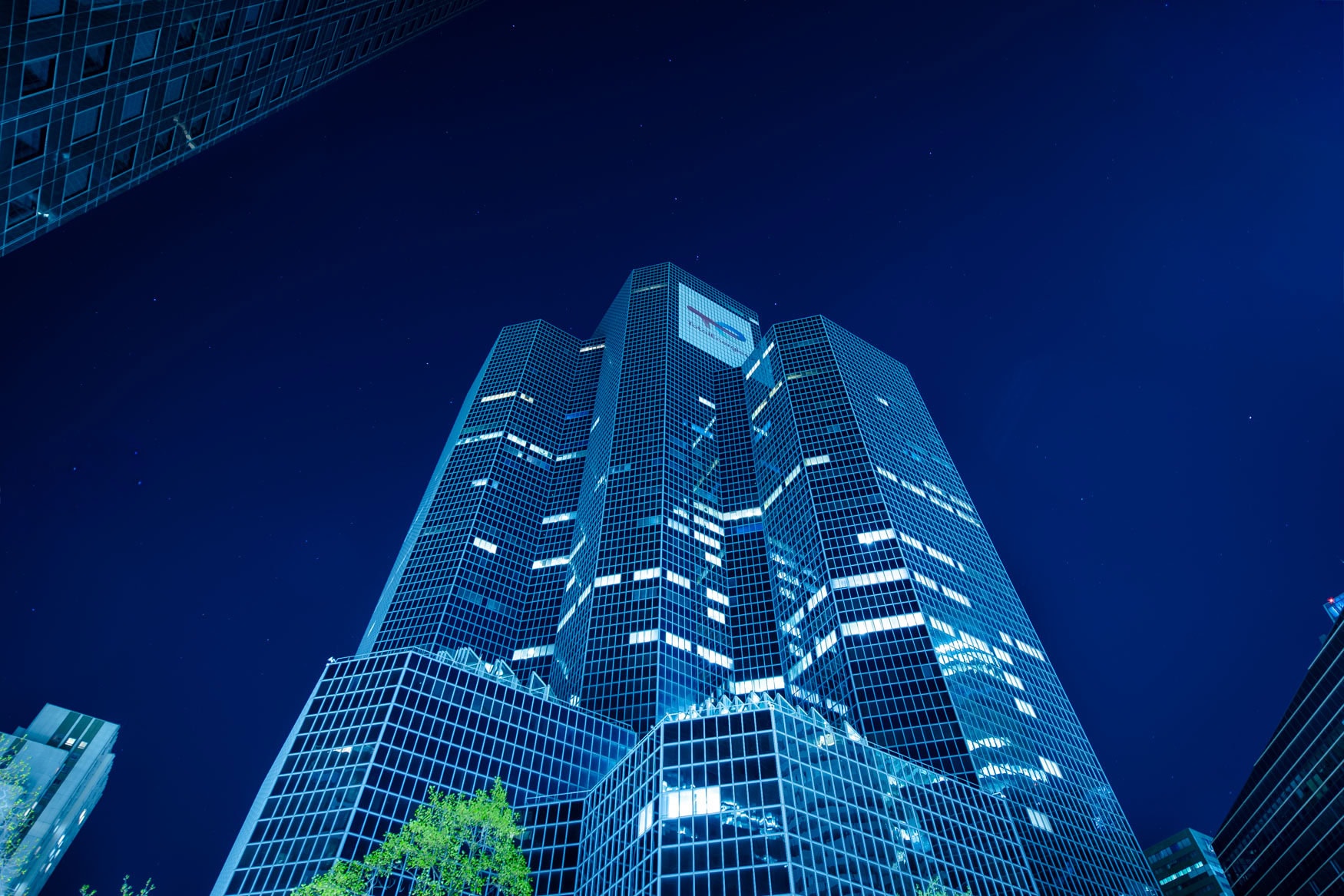 Gläserne Wolkenkratzer in Paris La Défense bei Nacht mit blauem Licht und beleuchteten Fenstern