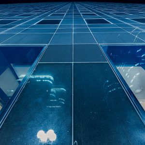 Glasfassade eines Hochhauses in Paris La Défense bei Nacht aus Froschperspektive mit Rasterlinien und Fenstern