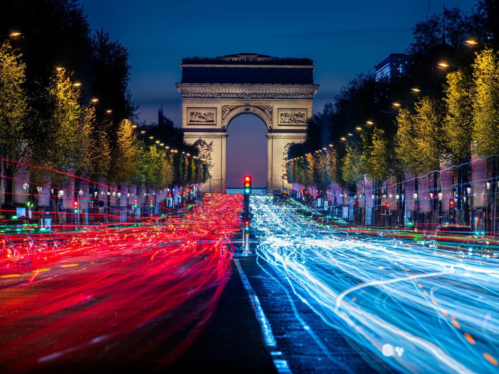 Triumphbogen in Paris mit roten und blauen Lichtspuren auf den Champs-Élysées bei Nacht