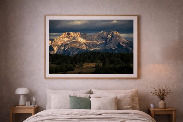 Großes gerahmtes Berglandschafts-Foto über einem Bett in einem dezenten Schlafzimmer mit Holz und warmem Licht.