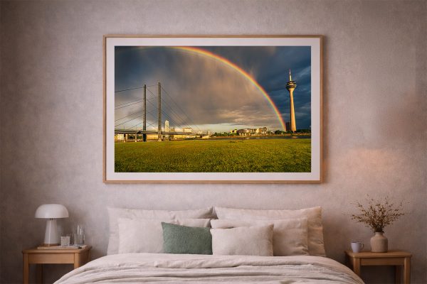 Großes gerahmtes Stadtlandschaft-Foto mit Regenbogen, Brücke und Turm über grüner Wiese an der Wand eines warmen Schlafzimmers.