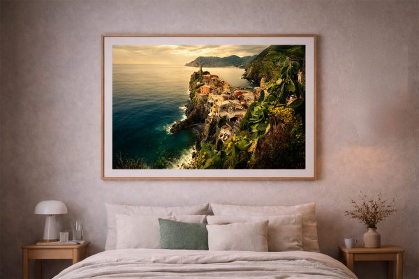 Großes gerahmtes Foto einer bunten Küstenstadt auf steiler Klippe über tiefblauem Meer, über einem weichen Bett im warmen Schlafzimmer.