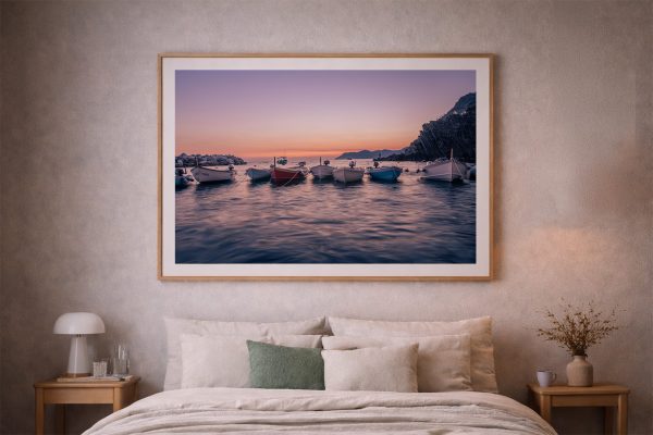 Fotografie mit Booten im ruhigen Meer bei Sonnenuntergang, im Holzrahmen über einem gemütlichen Bett im Schlafzimmer