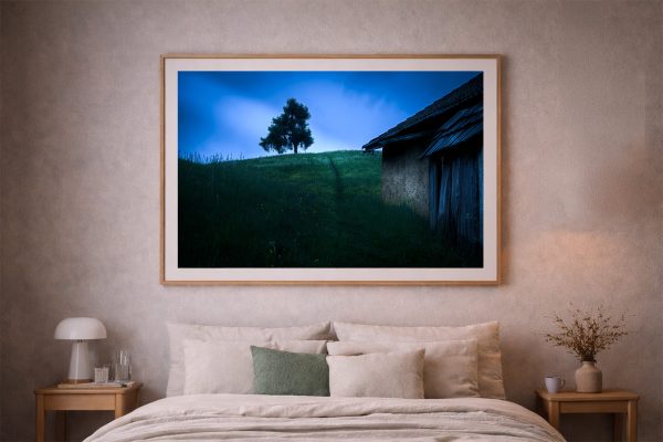 Großes Landschaftsfoto mit einsamem Baum auf Hügel und alter Scheune, gerahmt über einem Bett in einem warmen Schlafzimmer