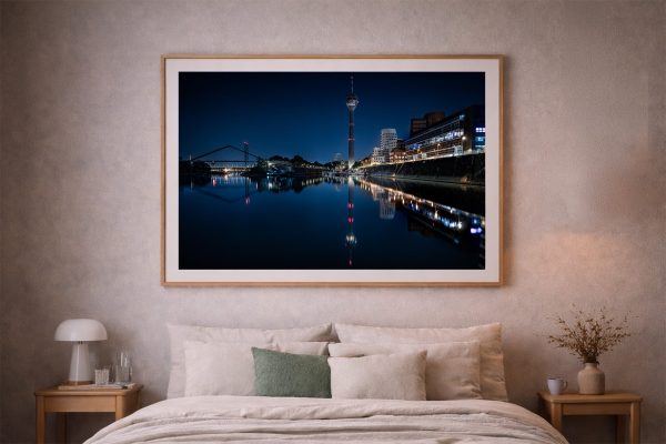 Großes gerahmtes Foto einer nächtlichen Stadt am ruhigen Fluss über einem Bett in sanft beleuchtetem Schlafzimmer