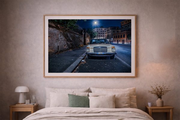 Fotografie eines hellen Oldtimers in einer nächtlichen Stadtstraße, frontal aufgenommen, gerahmt über einem Bett in einem ruhigen Schlafzimmer